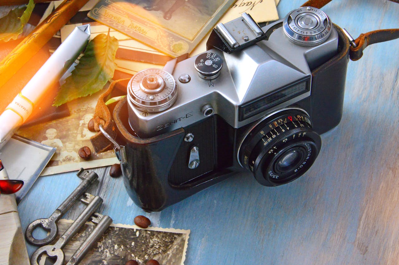 A classic film camera surrounded by nostalgic elements like keys, photos, and roasted coffee beans on a wooden table.